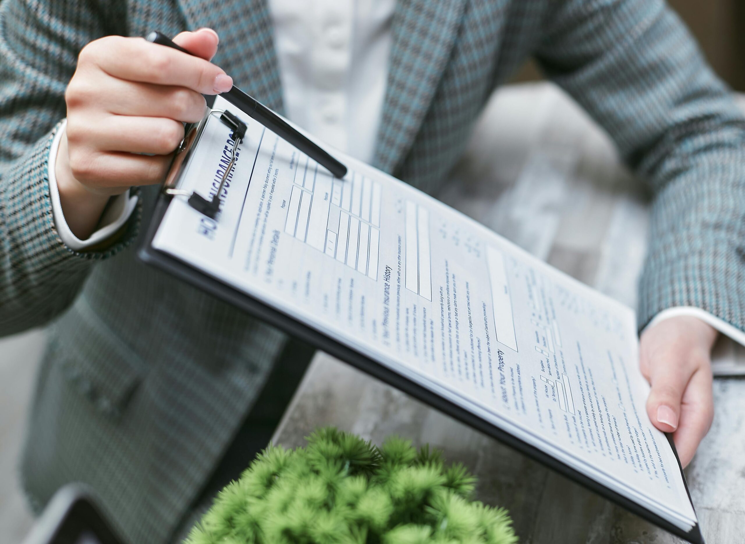 Person in business attire holding a clipboard with an inspection form and pointing to details with a pen