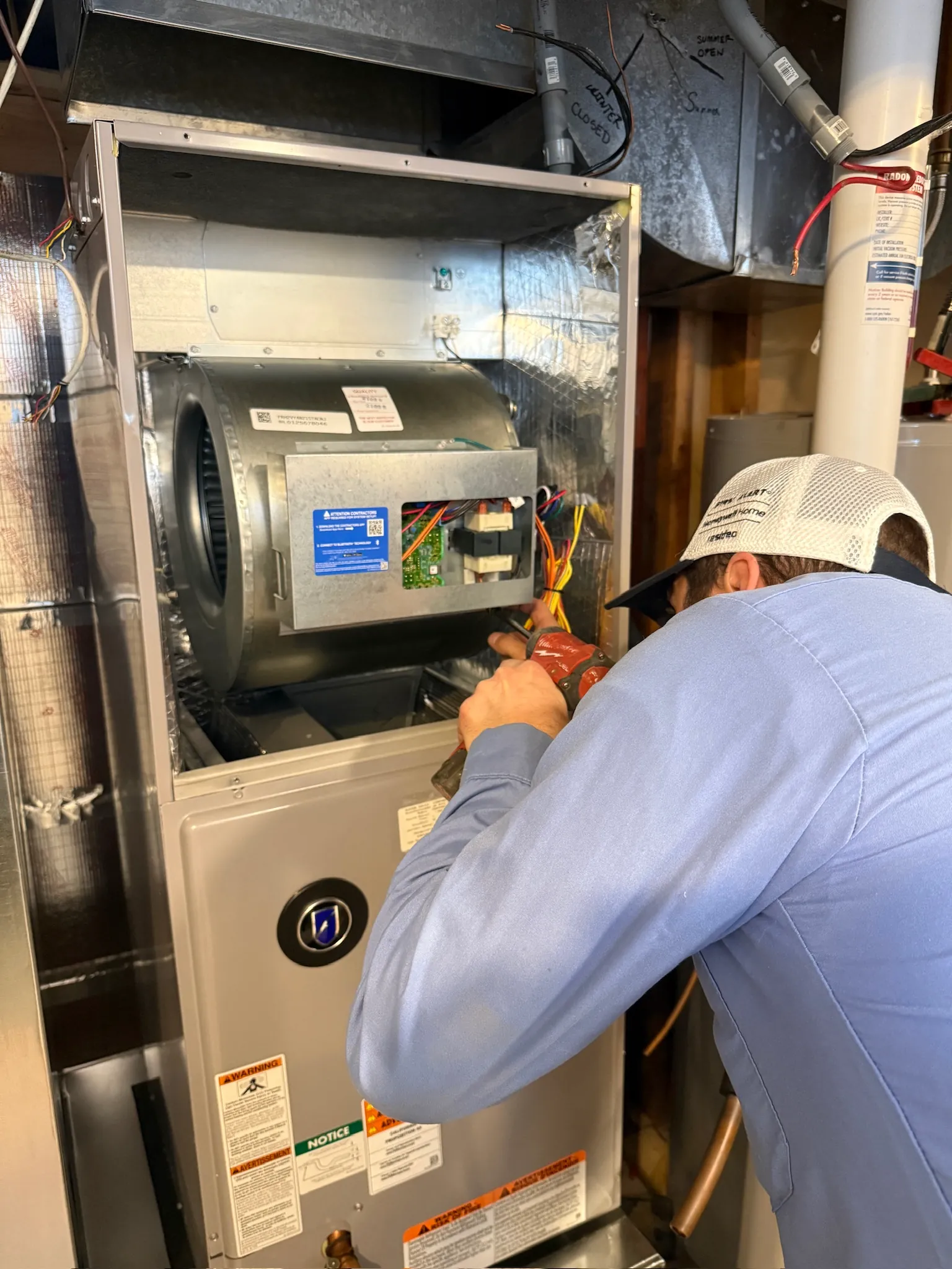 JOCO HVAC technician inspecting furnace electrical wiring and blower motor assembly