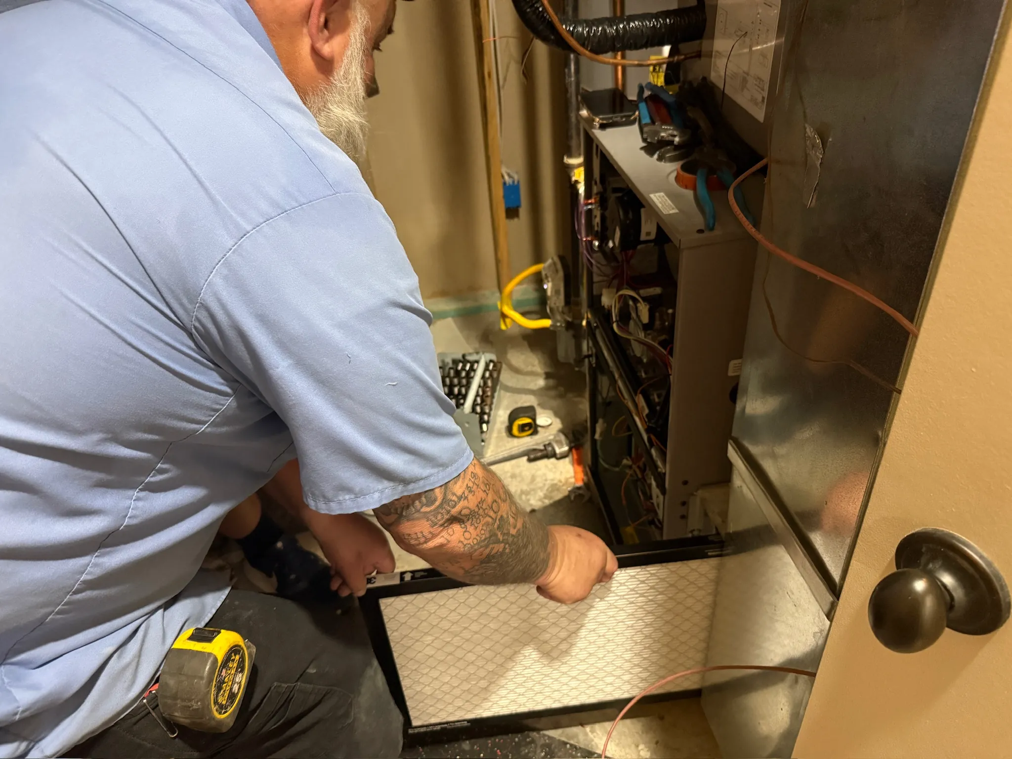 JOCO HVAC technician performing indoor furnace maintenance and filter change at a Kansas City home