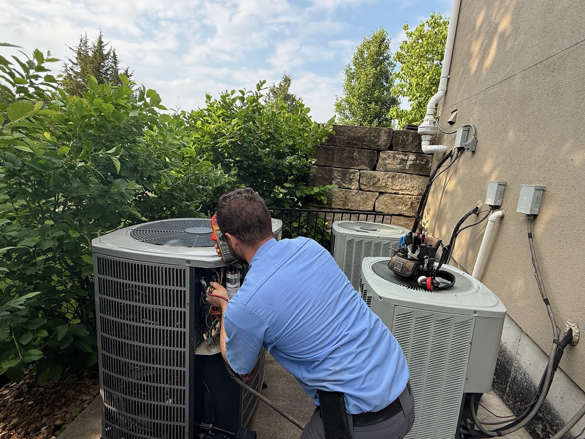 JOCO HVAC technician performing outdoor AC diagnostics during residential service call