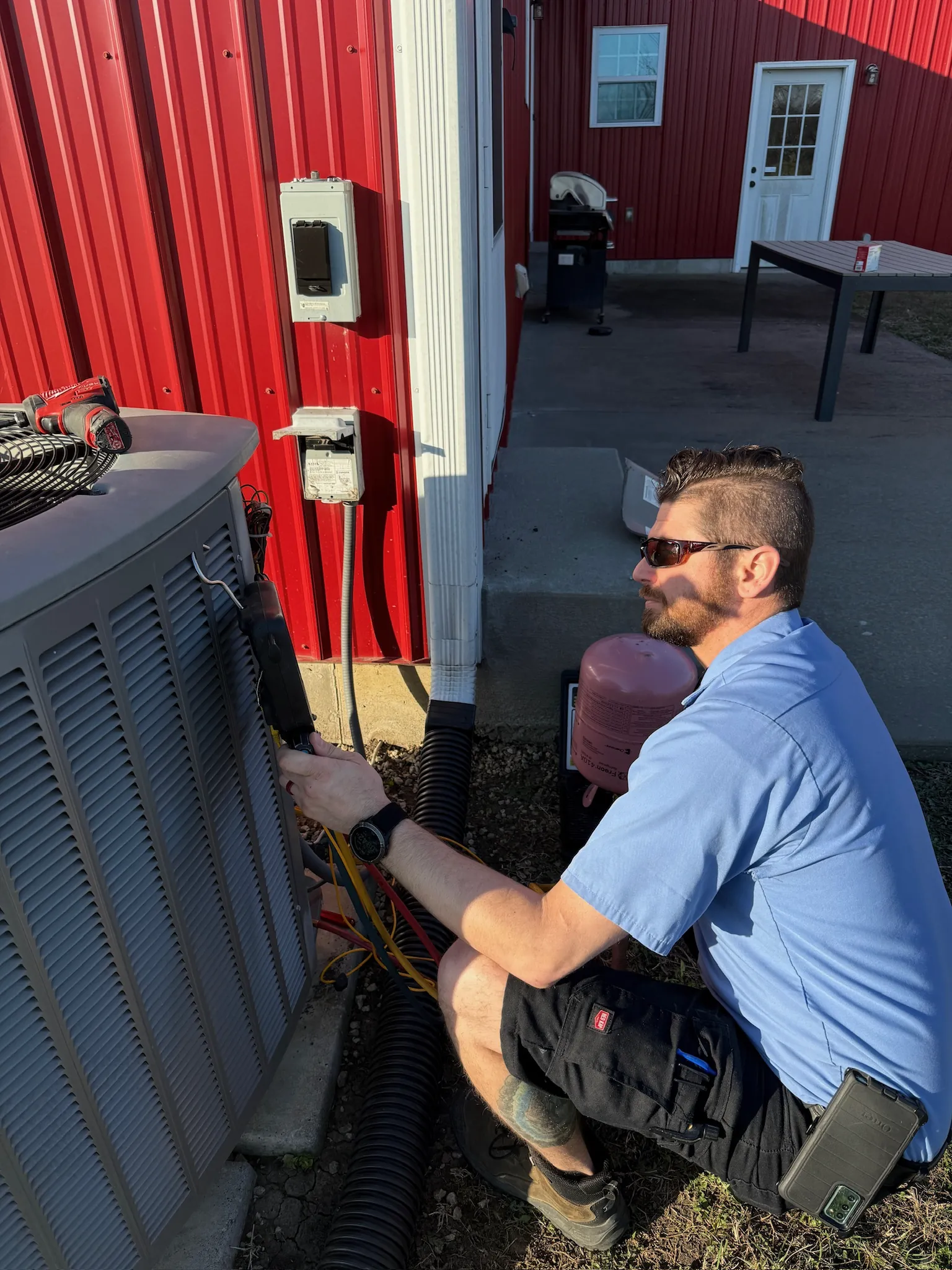 JOCO HVAC tech performing AC condenser repair with refrigerant gauges at a commercial property