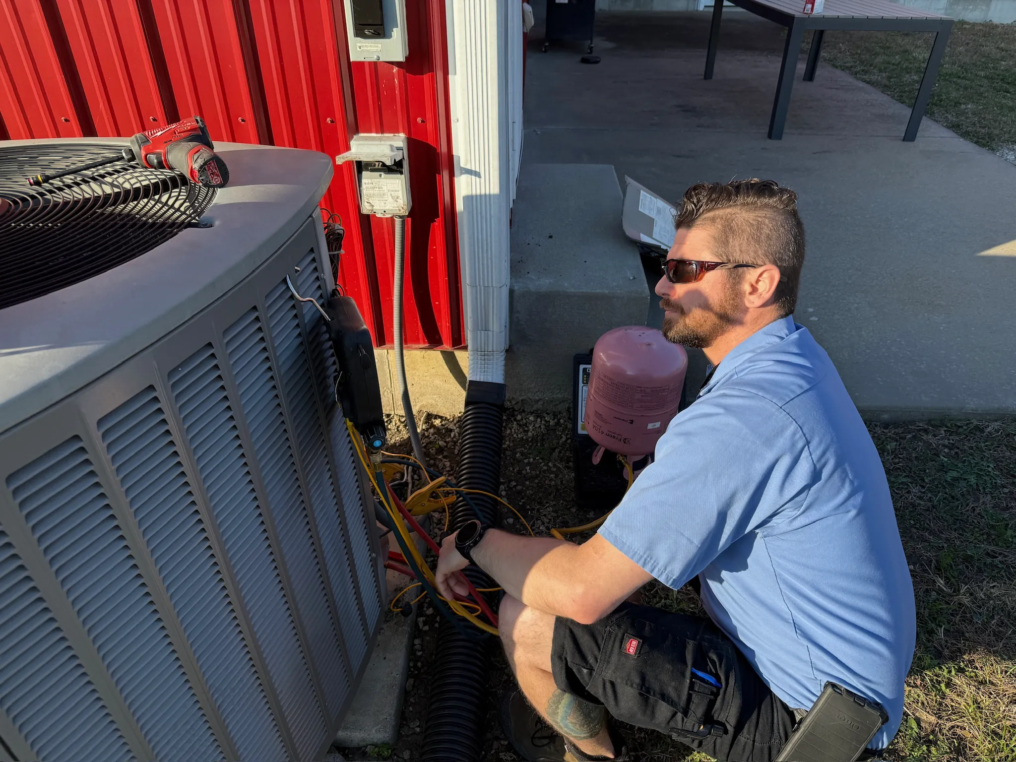JOCO HVAC technician servicing an outdoor air conditioning condenser unit at a commercial building in Johnson County